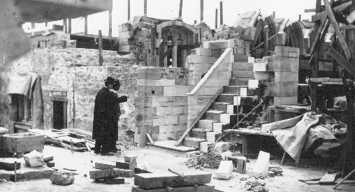 Raymond Pitcairn inspects the stairway under construction between the vestry and chapel, near the south transept. This stairway contains some remarkably complex planes shaped from a single stone, as is suggested by the one resting atop the railing and comprising parts of wall, tread, and riser.